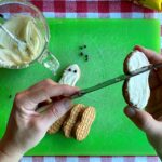 Author using knife to spread melted white chocolate onto cookie.