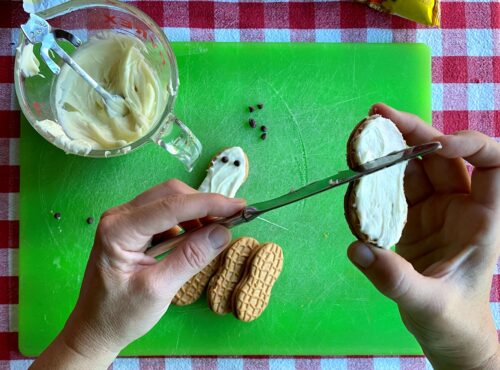 Author using knife to spread melted white chocolate onto cookie.