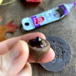 Hand holding a chocolate kiss with edible writing gel on the bottom of it