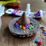 Witch's hat made from a cookie and chocolate kiss, covered in sprinkles.