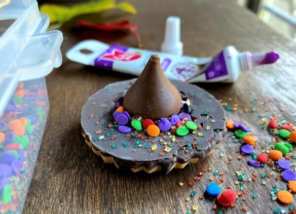 Witch's hat made from a cookie and chocolate kiss, covered in sprinkles.