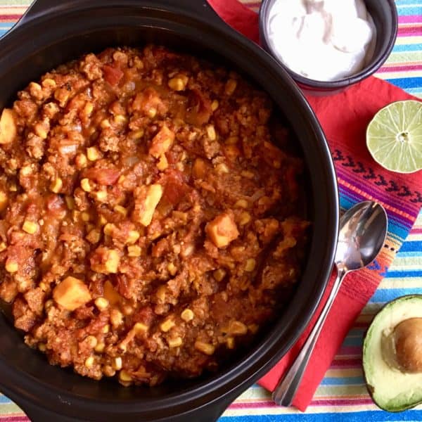 Autumn Harvest Chili in stockpot, with accompanients like avocado, lime, and yogurt alongside.